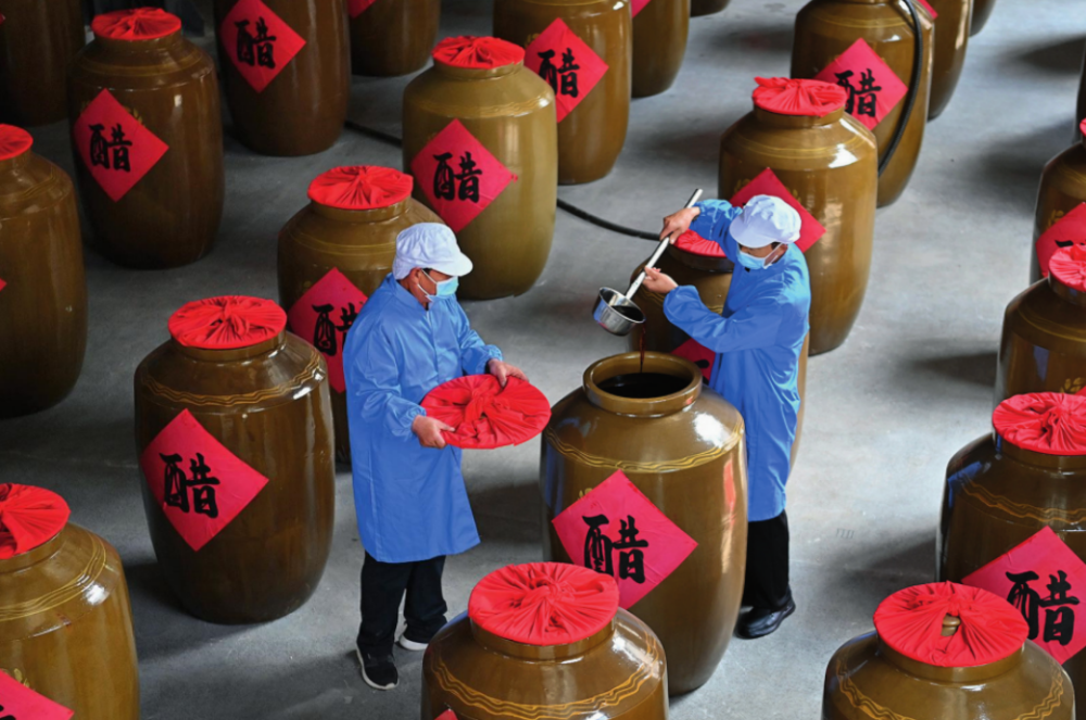工作人員在山西省長治市平順縣龍溪鎮(zhèn)龍鎮(zhèn)村農(nóng)旅產(chǎn)業(yè)融合發(fā)展示范園內(nèi)查看醋的成色（2024 年 5 月 10 日攝）楊晨光攝 / 本刊